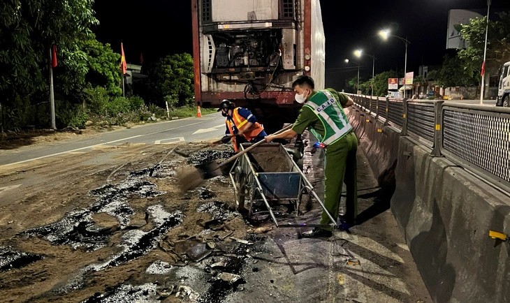 Công an xã Quảng Xuân cùng người dân xúc cát thu dọn vệt dầu loang trên quốc lộ 1, sau tai nạn từ 9h30 đến 11h đêm - Ảnh: P.P.